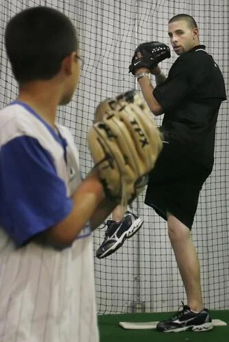 Coach Jeff Allison demonstrating a pitching delivery to a young catcher